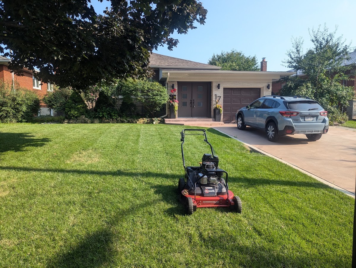 Freshly striped front lawn with mower in front of a suburban home